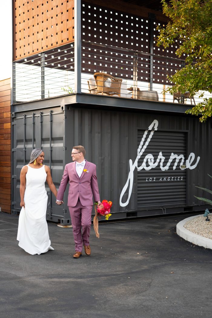 Groom Outdoors Walking with Bride Wearing Minimalist Wedding Dress Called Claudia Dawn by Maggie Sottero