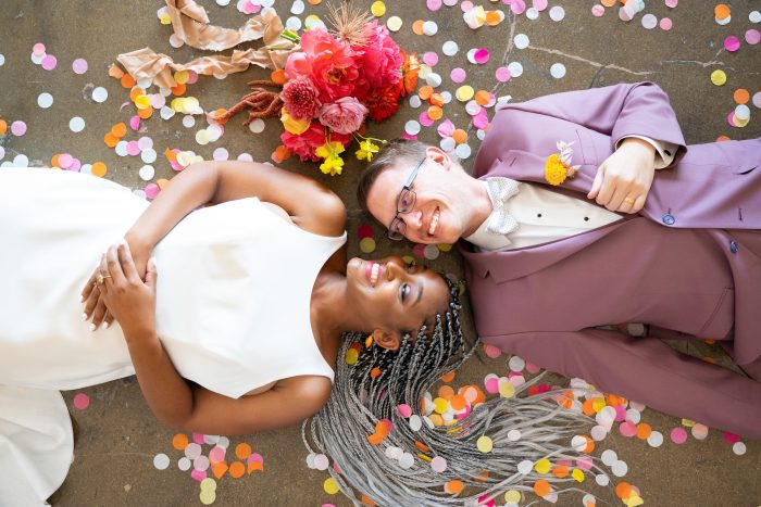 Bride and Groom Laying on the Ground Surrounded by Colorful Confetti at Citrus Wedding