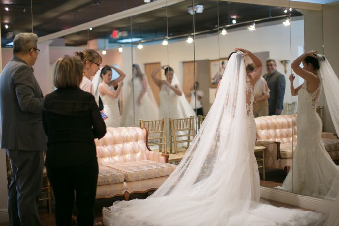 Bride Trying on Veil with Wedding Dress by Maggie Sottero