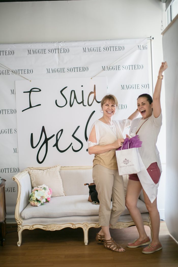 Bride with "I Said Yes" sign in a bridal boutique