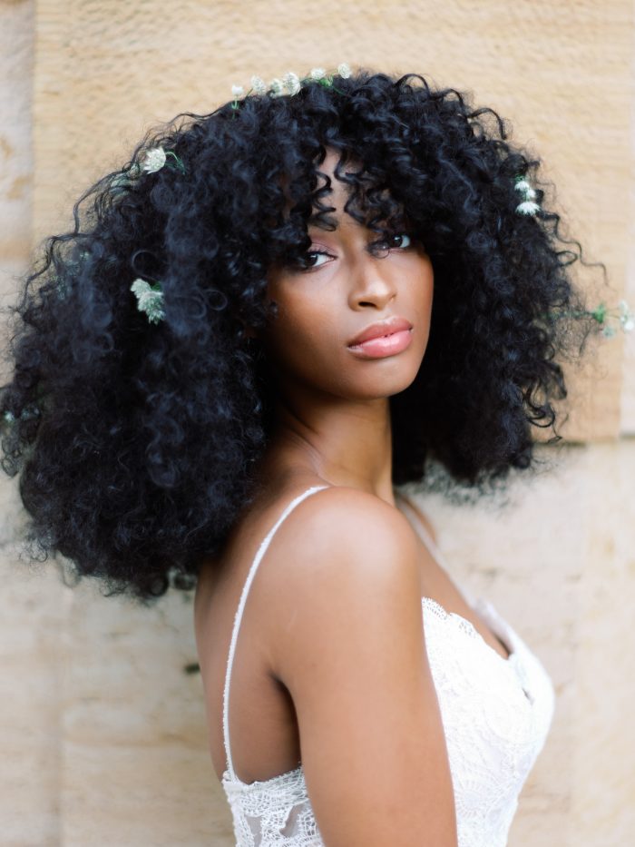 Black Bride Wearing Natural Curly Wedding Hairstyle with Flowers in Hair