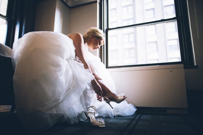 Bride Putting on White Wedding Shoes