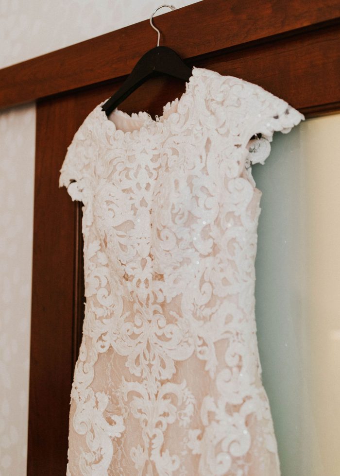 Cap-Sleeve Lace Wedding Dress Called Tuscany Leigh by Maggie Sottero Hanging on Door