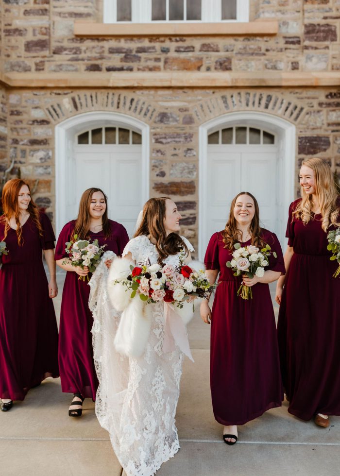 Real Bride Wearing Romantic Lace Wedding Dress Called Tuscany Leigh by Maggie Sottero and Walking With Her Bridesmaids Wearing Burgundy Maxi Dresses