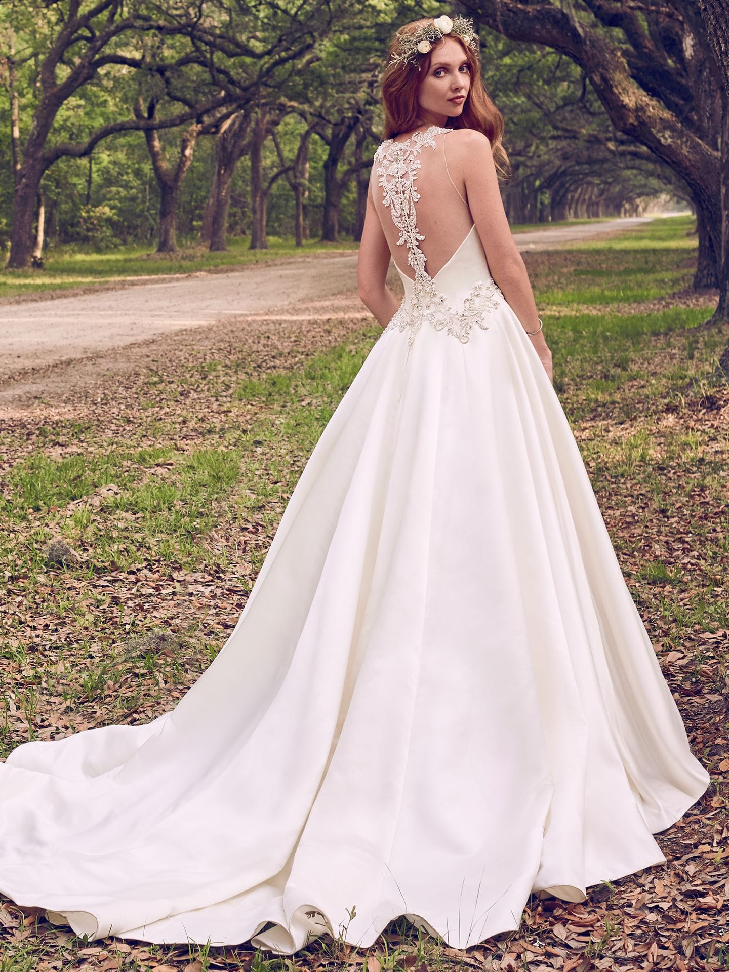 Beautiful statement-back wedding dresses from Maggie Sottero and Sottero and Midgley - Beaded lace motifs and Swarovski crystals adorn the waistline and illusion open back in this Gala Satin wedding dress. Corianne by Maggie Sotter.