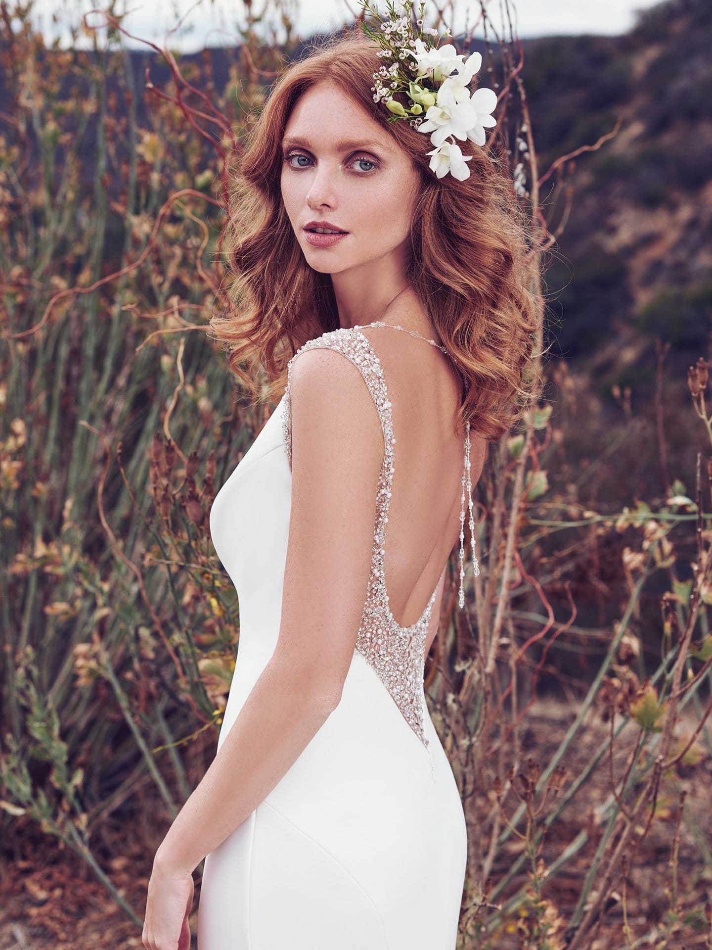 Beautiful statement-back wedding dresses from Maggie Sottero and Sottero and Midgley - Simple yet chic, this Aldora Satin wedding dress features illusion and Swarovski crystals accenting the shoulders, gliding into a shimmering ribbon of pearls and beading that ties in the plunging back, also trimmed in illusion and Swarovski crystals. Evangelina by Maggie Sottero.