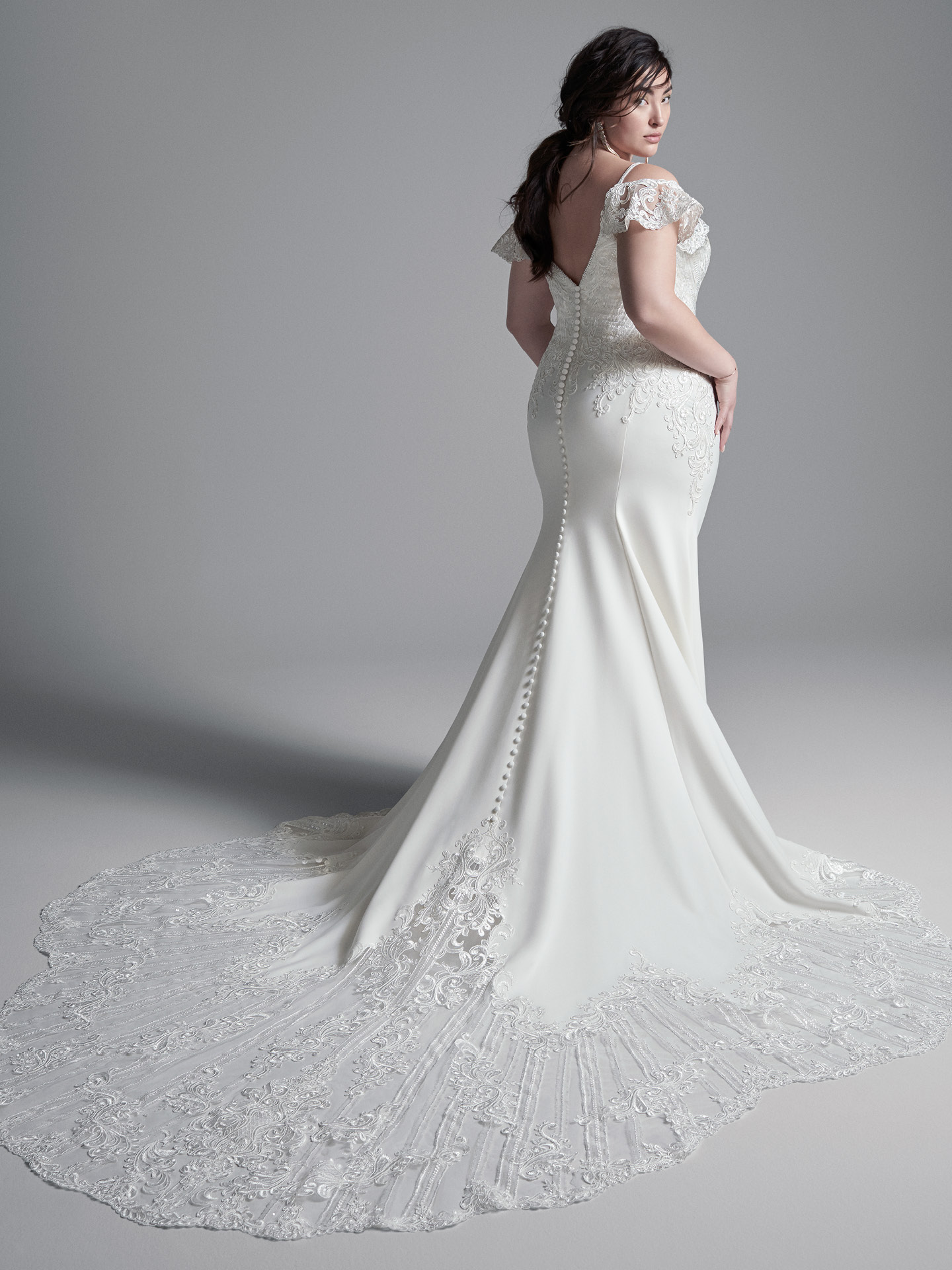 Modèle Curvy portant une robe de mariée à manches à épaules dénudées grande taille appelée Bracken faite par Sottero et Midgley