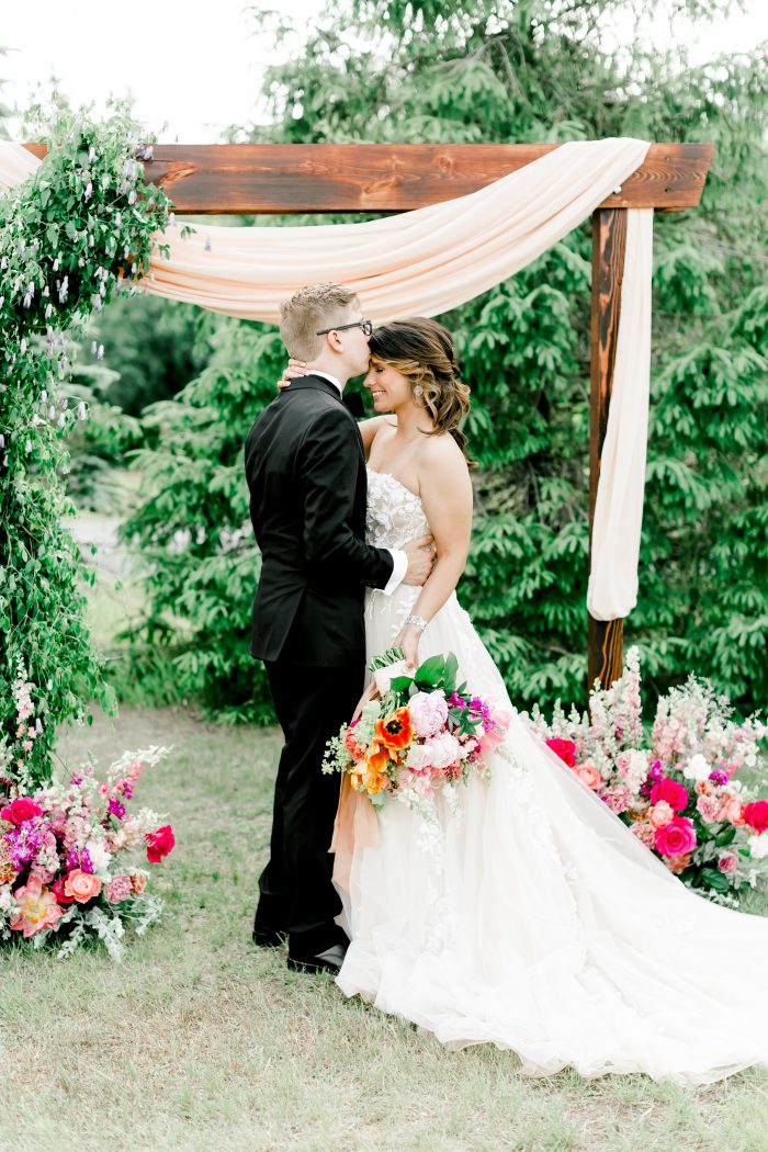 Groom Kissing Bride's Forehead While Bride Wearing Floral A-line Wedding Dress Zareen by Maggie Sotter