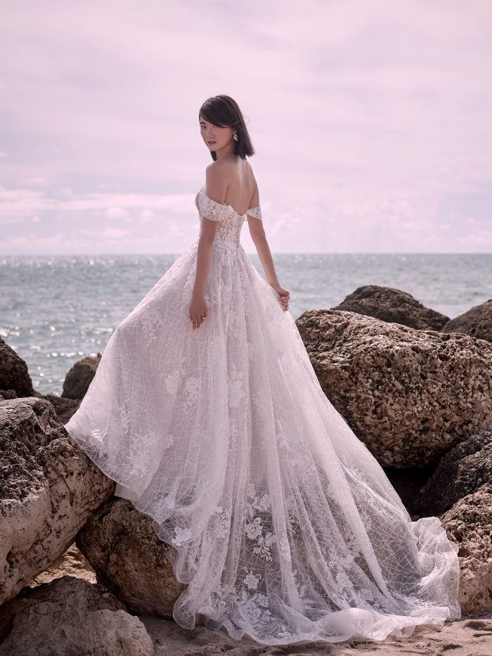 Model on Beach Wearing Fairytale Off-the-Shoulder Bridal Gown Called Parker by Sottero and Midgley