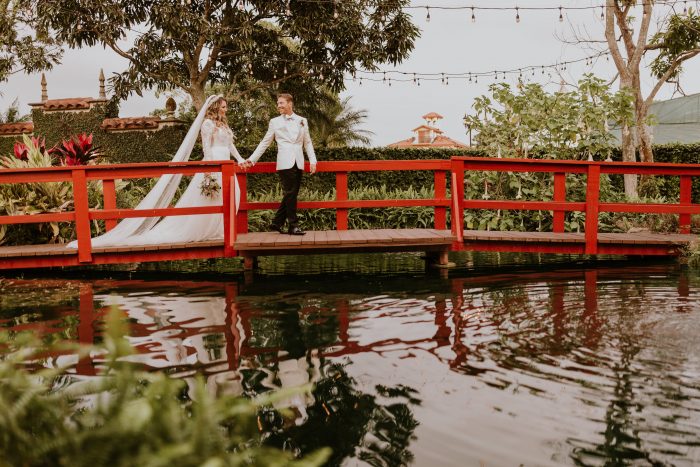 Groom on Red Bridge with Real Bride Wearing Boho Flower Crown and Boho Wedding Dress by Maggie Sottero
