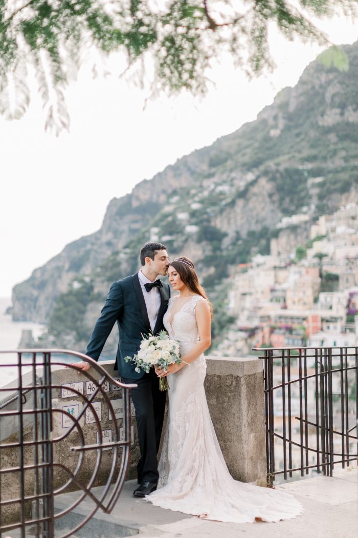 Groom Kissing Bride Wearing Lace Sheath Wedding Dress by Maggie Sottero in Positano Italy