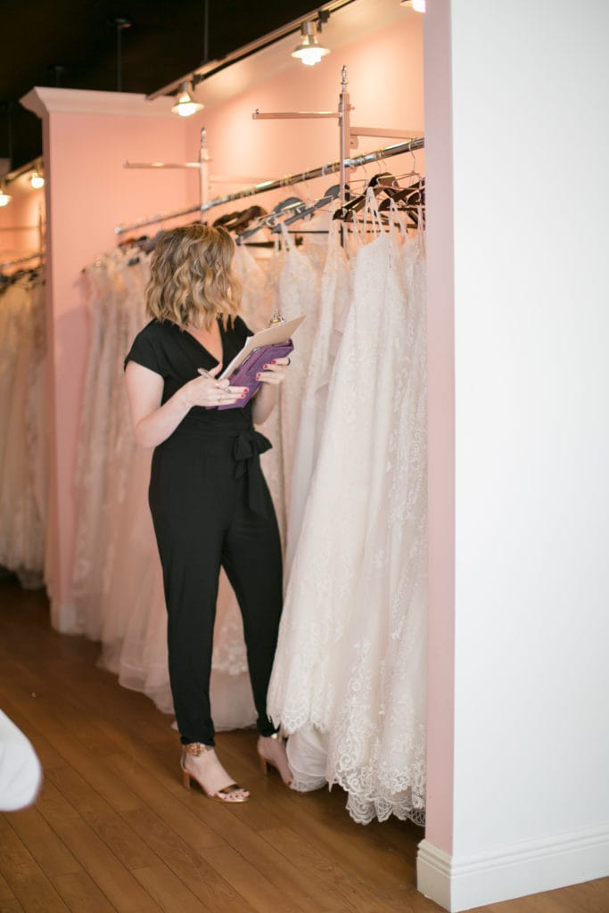 Bridal Stylist Browsing Row of Wedding Dresses at a Local Boutique