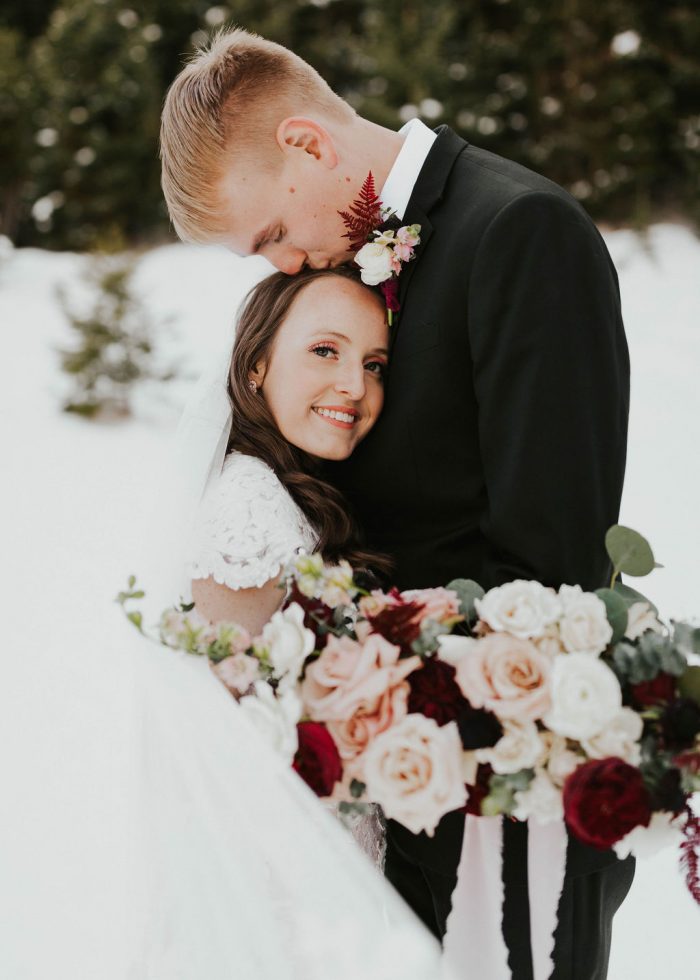 Groom Kissing Bride Wearing a Romantic Winter Wedding Makeup Look and Maggie Sottero Modest Wedding Gown