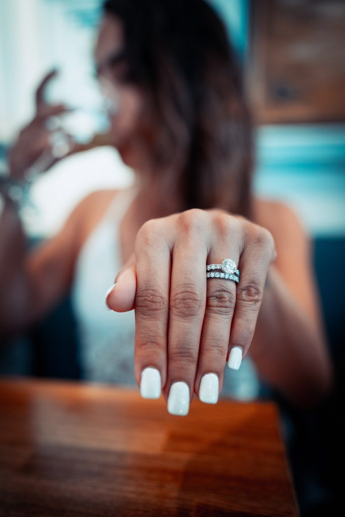 Woman with White Painted Nails HOlding out Hand with Engagement Ring and Wedding Band on Her Finger