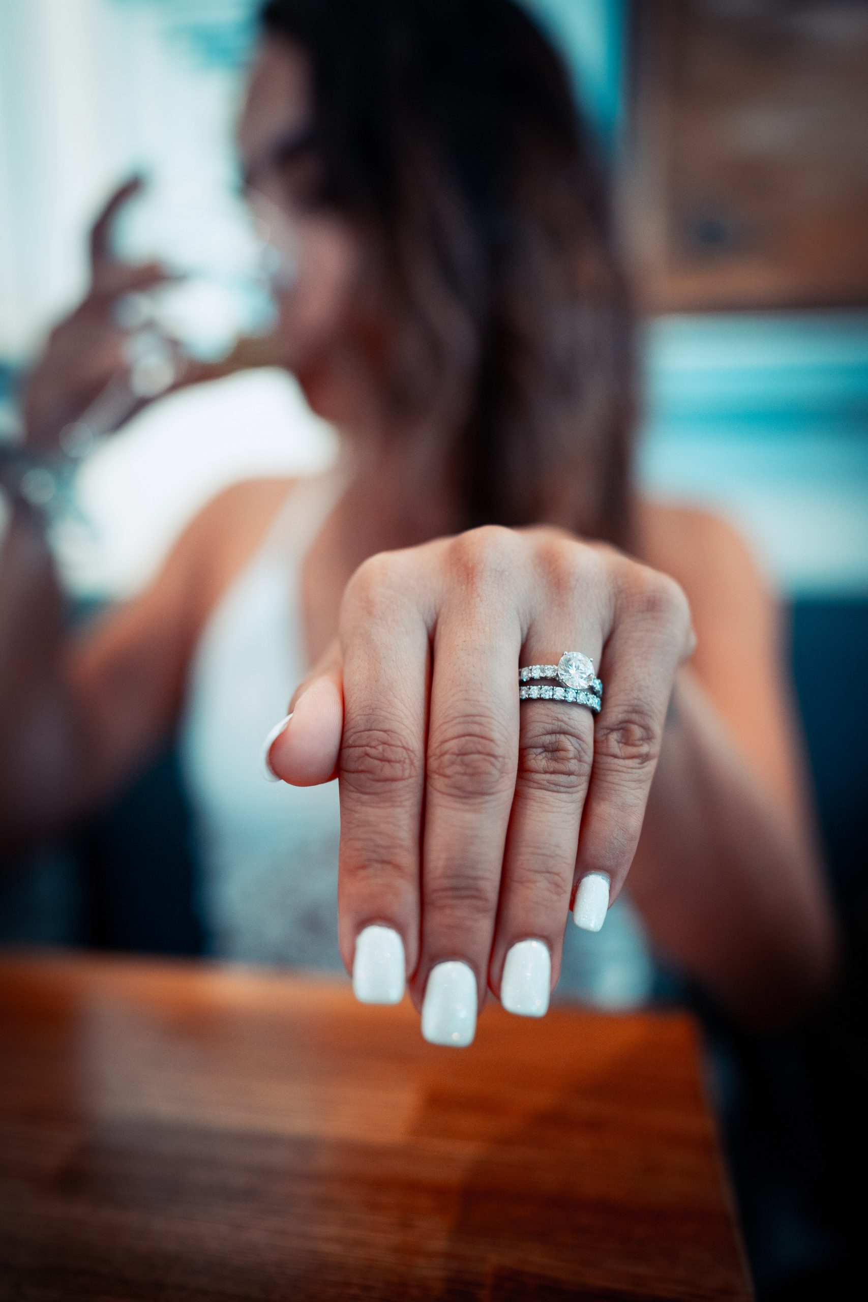 Femme avec des ongles peints en blanc tenant la main avec une bague de fiançailles et une alliance sur son doigt