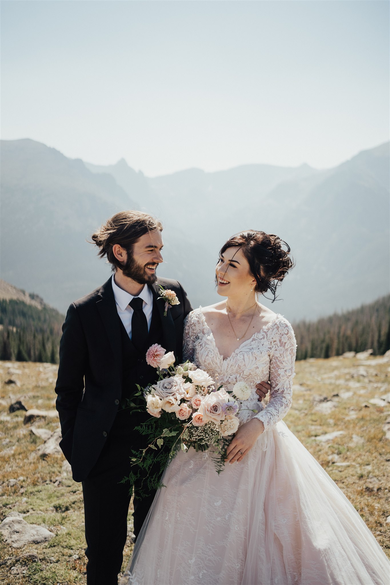 Mariée portant une robe de mariée A-ligne romantique debout avec son mari avec fond de montagne appelé Zander par Sottero et Midgley 