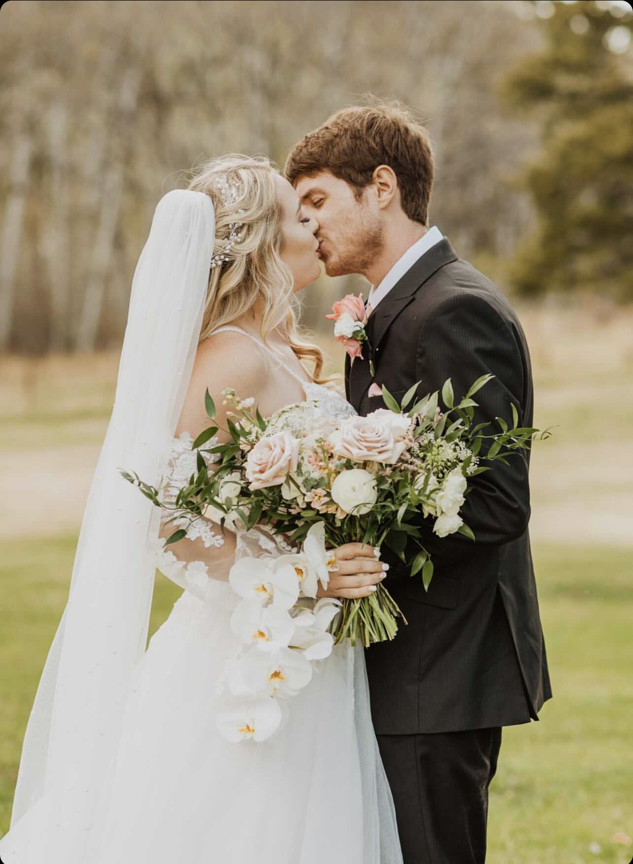 Les mariés s'embrassent avec la mariée vêtue d'une robe appelée Stevie par Rebecca Ingram