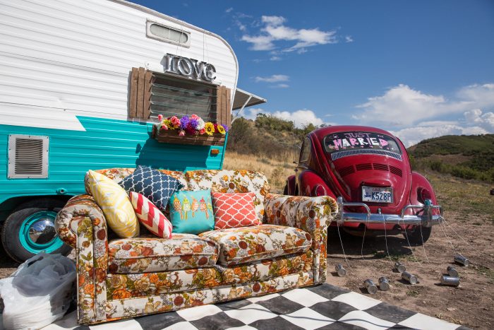 Couch in front of trailer and a red car in the mountains