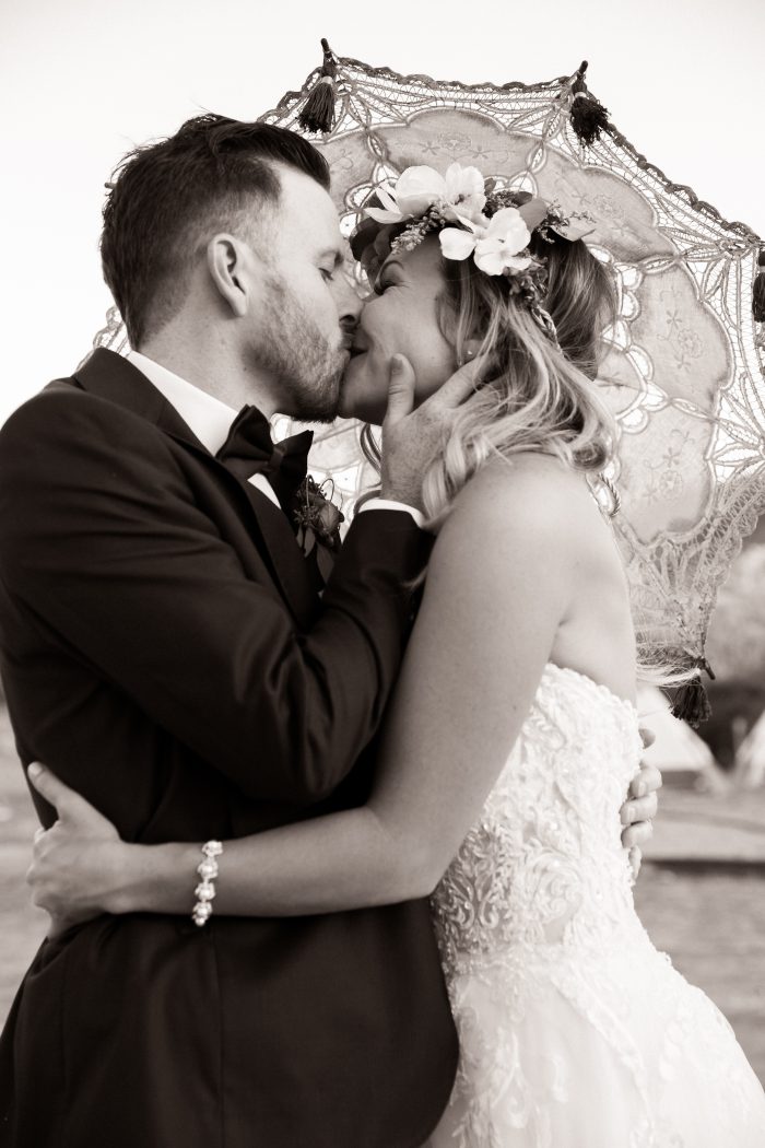 Bride wearing Watson by Sottero and Midgley with a Parasol kissing her groom