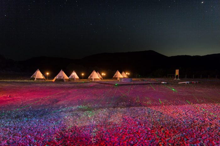 Tents lit up in a colorful field