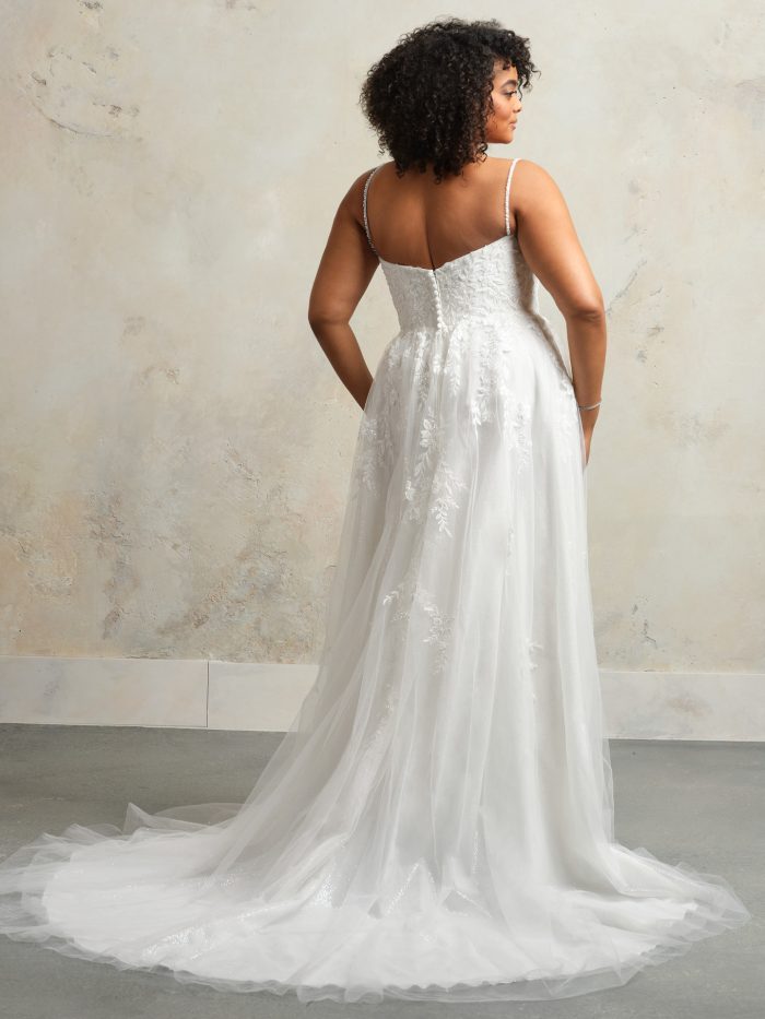 Back view of Rebecca Ingram Catherine A-line wedding dress featuring delicate straps, floral lace appliqués, covered buttons, and a flowing tulle train.