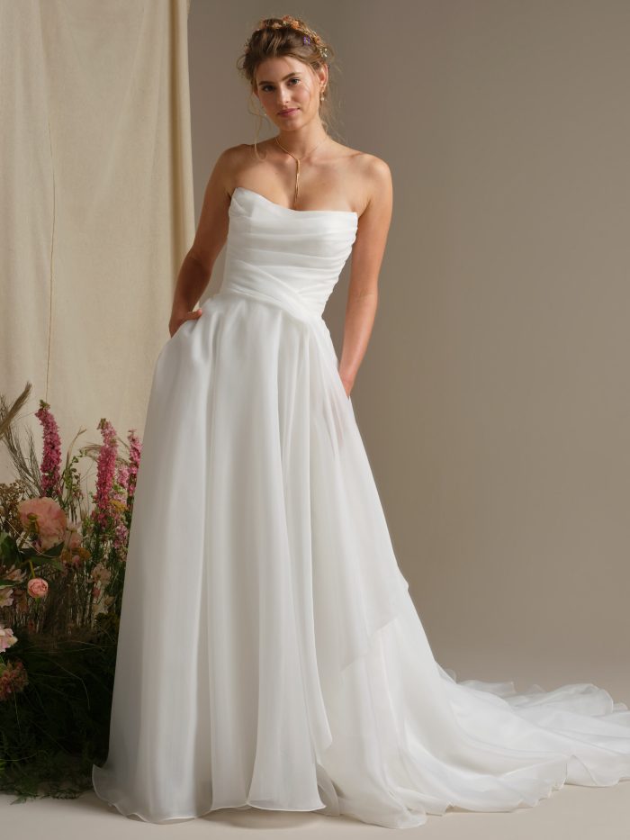 Rebecca Ingram Dezi ballgown wedding dress featuring a strapless ruched bodice, full flowing skirt, and pockets.