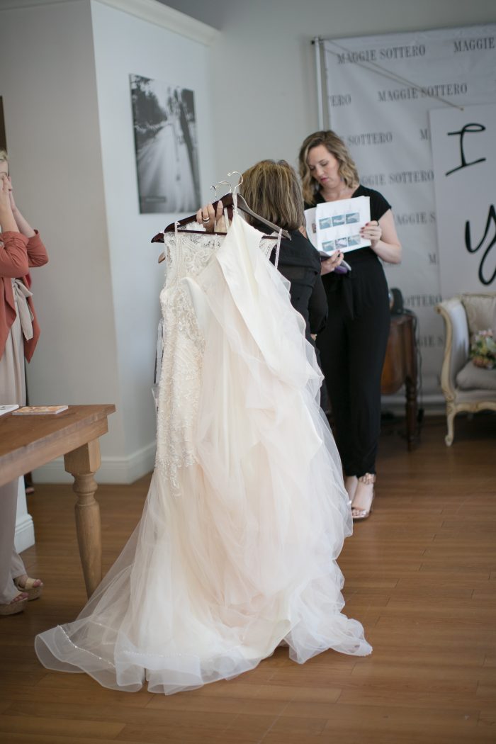 Stylist Holding Selections of Wedding Dresses for Brides to Try On