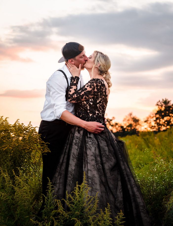 Bride Kissing Groom Wearing Black Ball Gown Called Zander by Sottero and Midgley