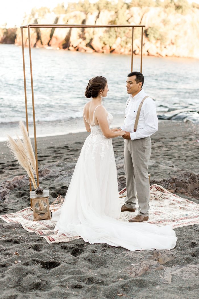 Bride and Groom Saying Wedding Vows in Front of Wedding Arch on Black Sand Beach