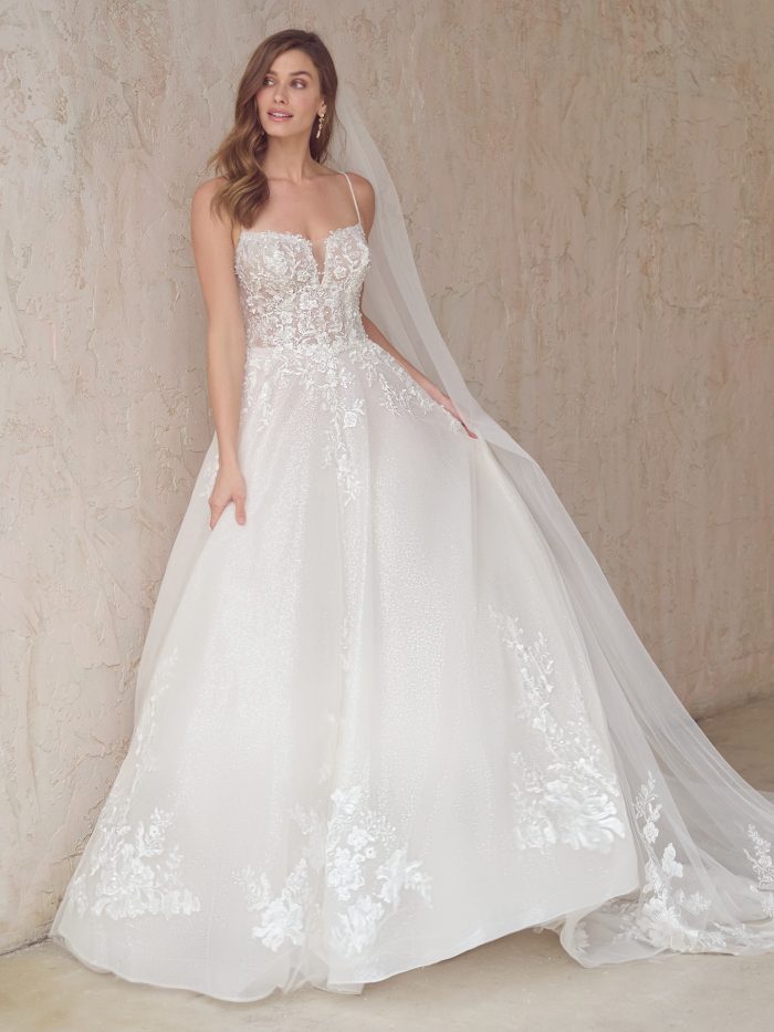 Casey ballgown wedding dress featuring a delicate lace bodice with a plunging illusion neckline, dainty spaghetti straps, and a glitter tulle skirt for soft, romantic volume