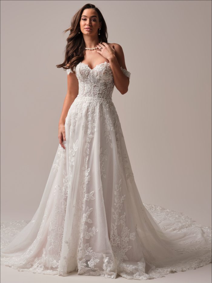 Everleigh A-line wedding dress featuring an off-the-shoulder sweetheart neckline, allover floral lace, and a soft tulle skirt with a romantic, flowing train