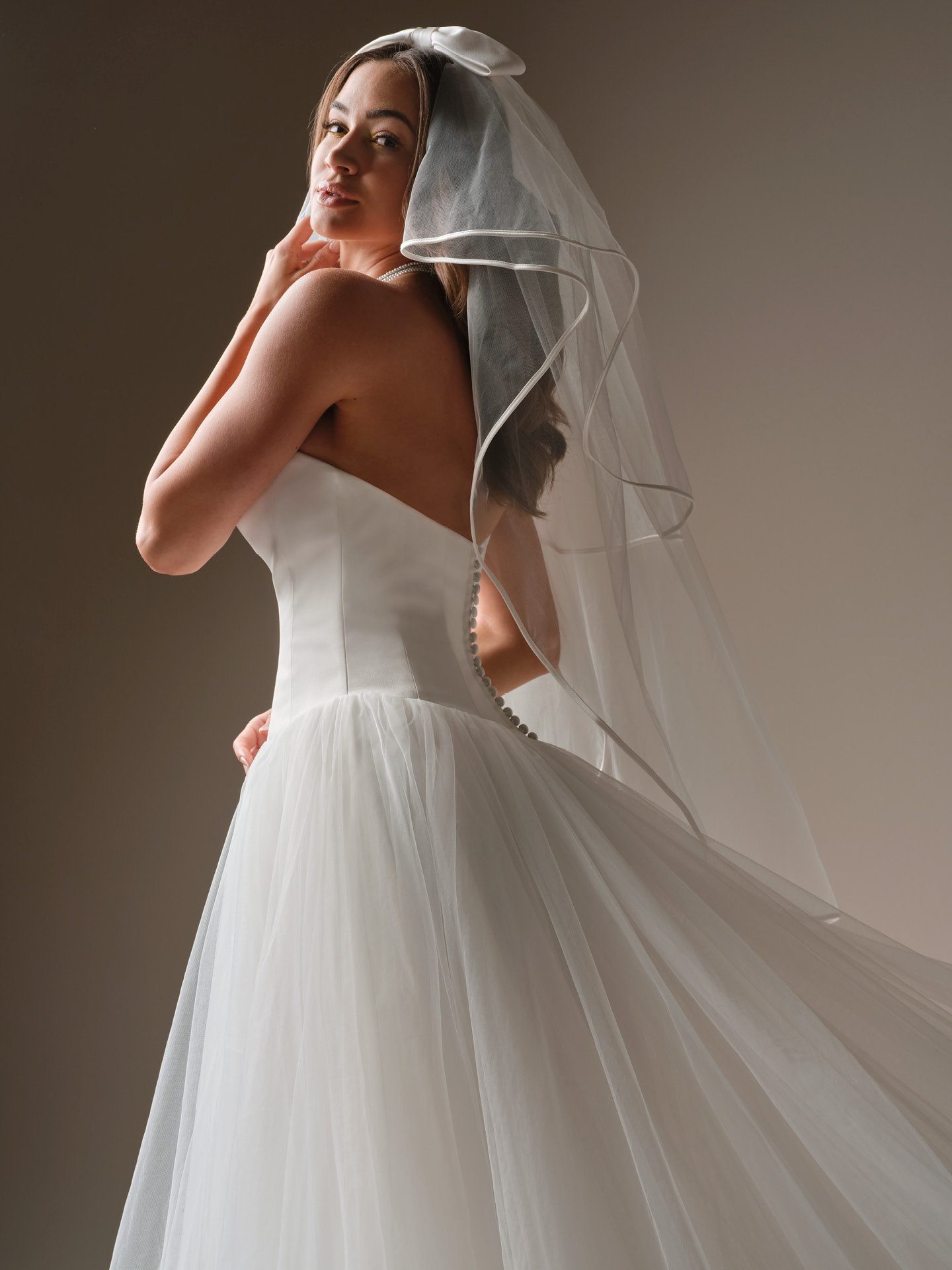 Shirley ballgown wedding dress back view with covered button closure, flowing tulle skirt, and a classic veil for an effortlessly timeless bridal look