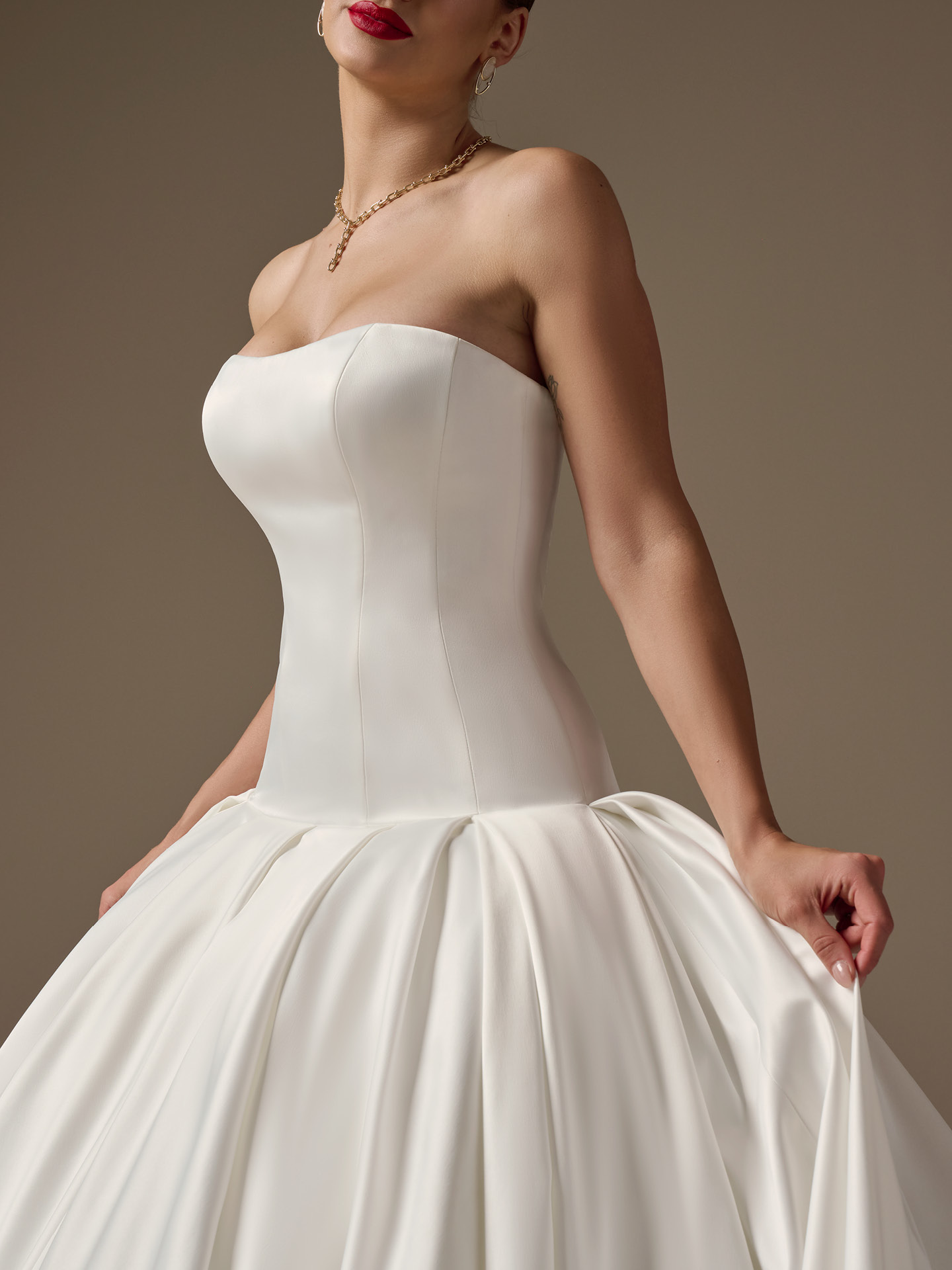Adair strapless satin wedding dress close-up highlighting the clean, structured bodice, soft scoop neckline, and artful draping at the dropped waist for a chic, minimalist bridal statement