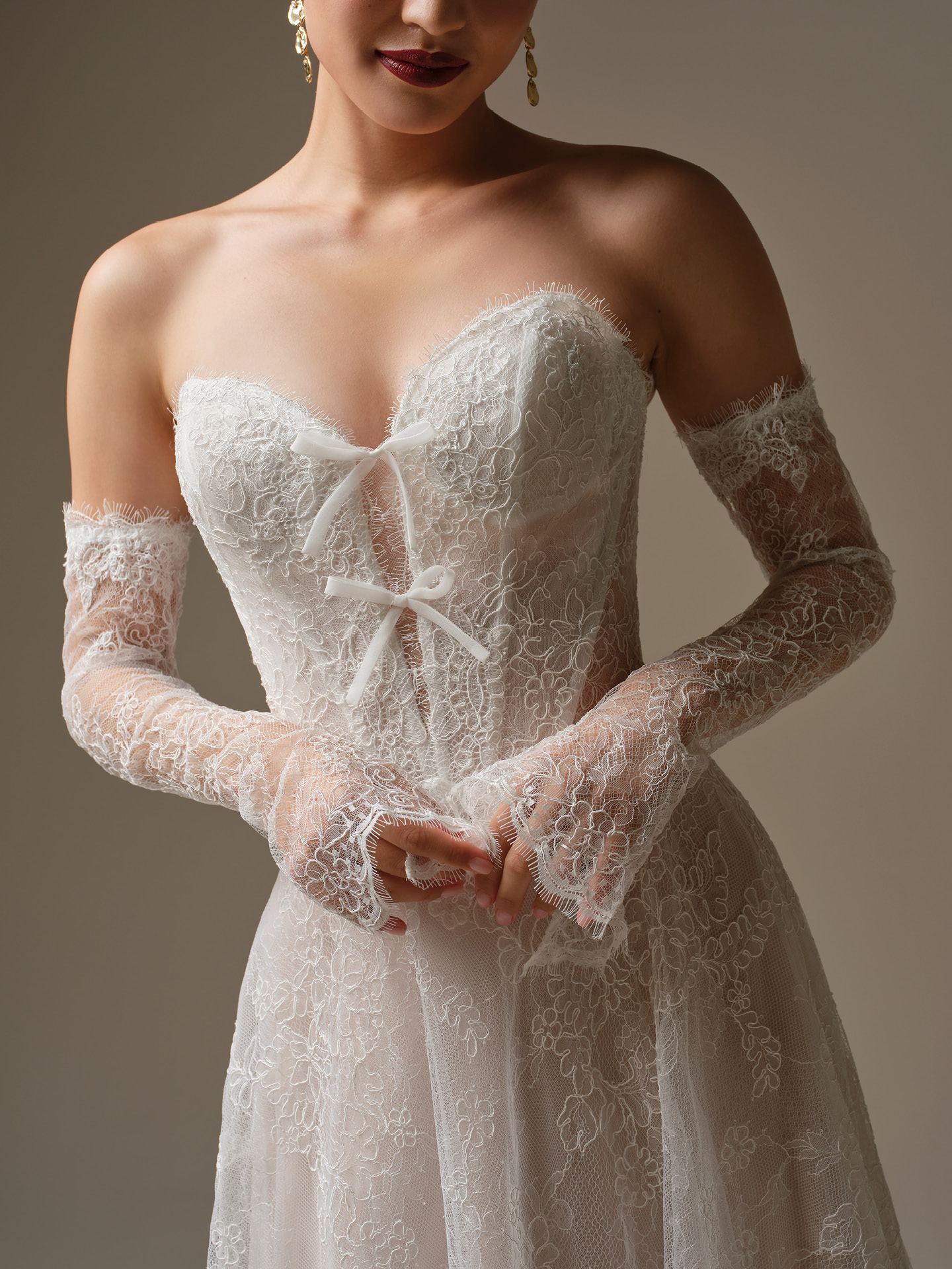 Granger A-line wedding dress close-up of strapless lace bodice with dainty bow detailing, sheer illusion structure, and detachable long lace sleeves with intricate floral patterns