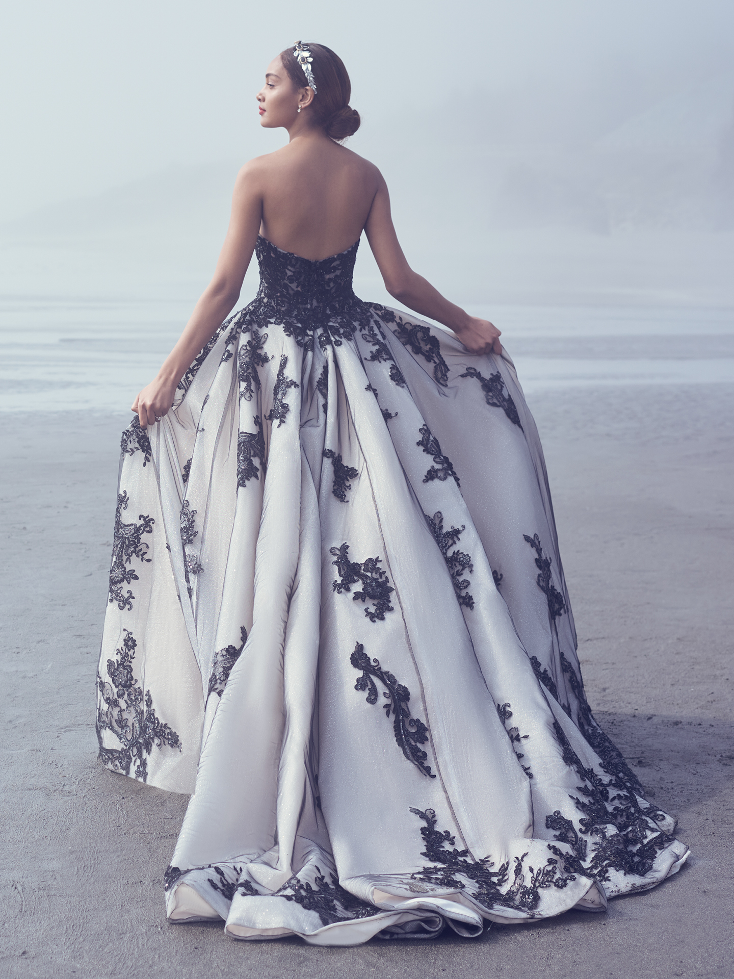 Mariée marchant sur la plage portant une robe de mariée glamour appelée Norvinia par Sottero et Midgley