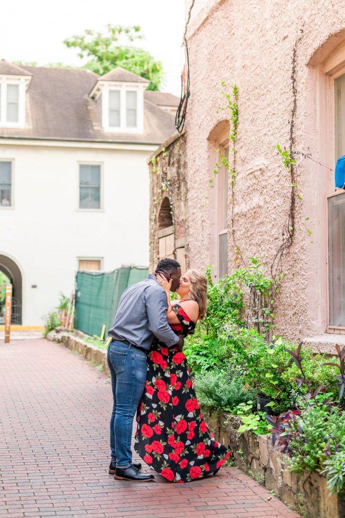 Curvy Bride with African American Groom Kissing While Taking Engagement Photos