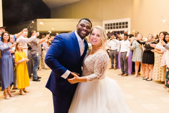 African American Groom Smiling and Holding Hands with Real Bride During Florida Wedding Reception
