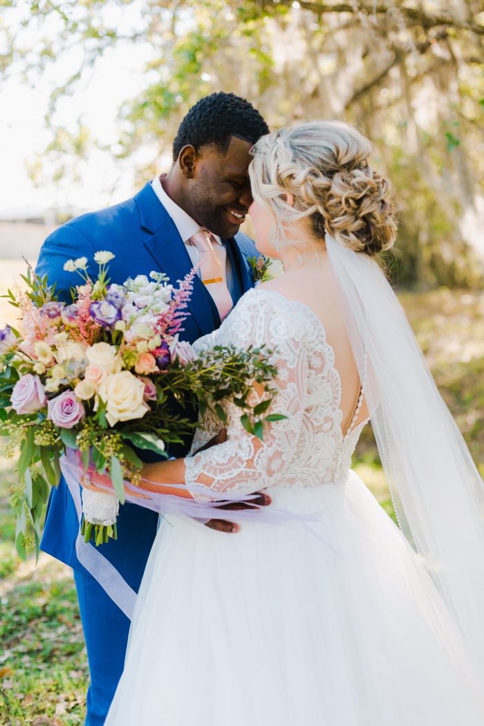 Groom Smiling at Curvy Bride Wearing Plus Size Lace Ball Gown Wedding Dress Called Mallory Dawn by Maggie Sottero