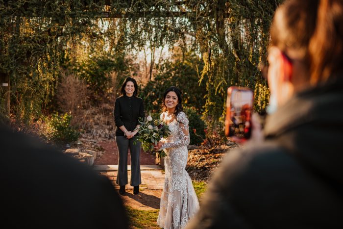 Bride Standing by Officiant During Wedding Ceremony While Guests Are Social Distancing