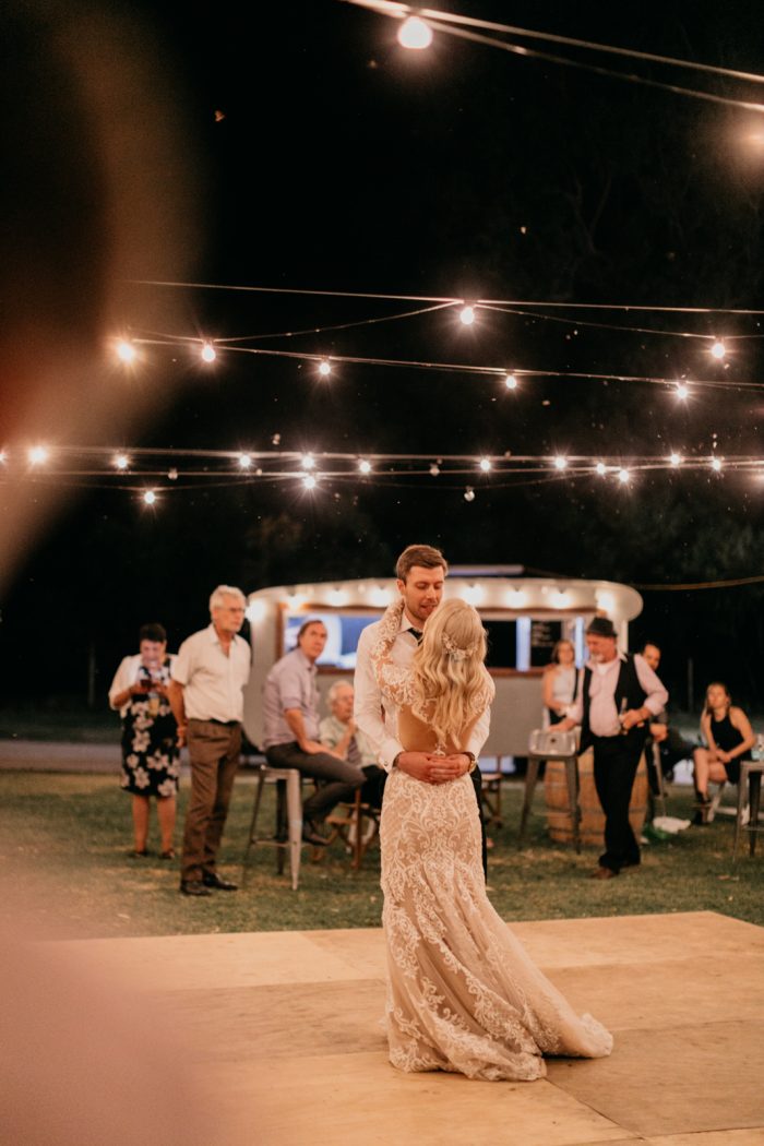Groom Dancing Under Fairy Lights with Real Bride Wearing Lace Wedding Dress Dakota by Sottero and Midgley