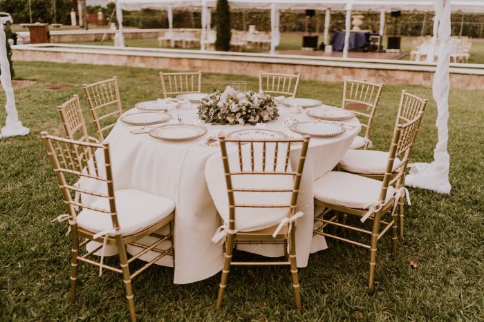 Round Table Covered with White Cloth and Gold Chairs at Backyard Wedding to Help Guests Social Distance