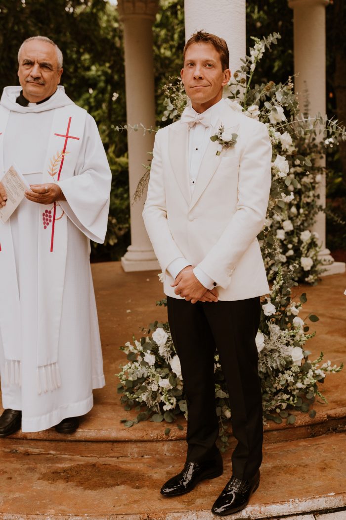Groom Standing with Priest As He Watches His Bride Walk Down the Aisle
