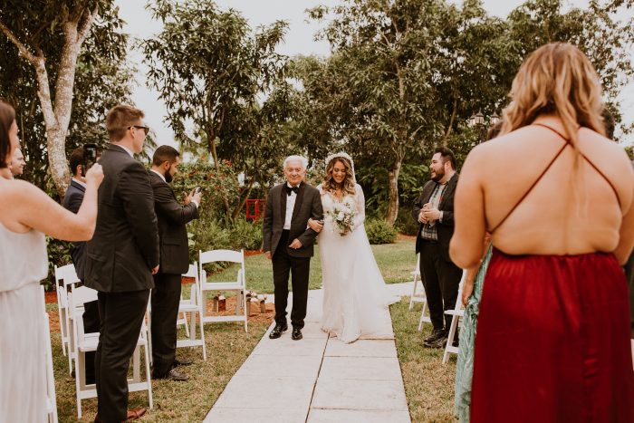 Father of the Bride Walking Bride Down the Aisle During Backyard Wedding While Guests are Social Distancing