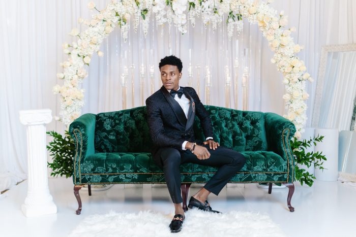 Black Groom Sitting on Luxurious Green Couch at Wedding Reception