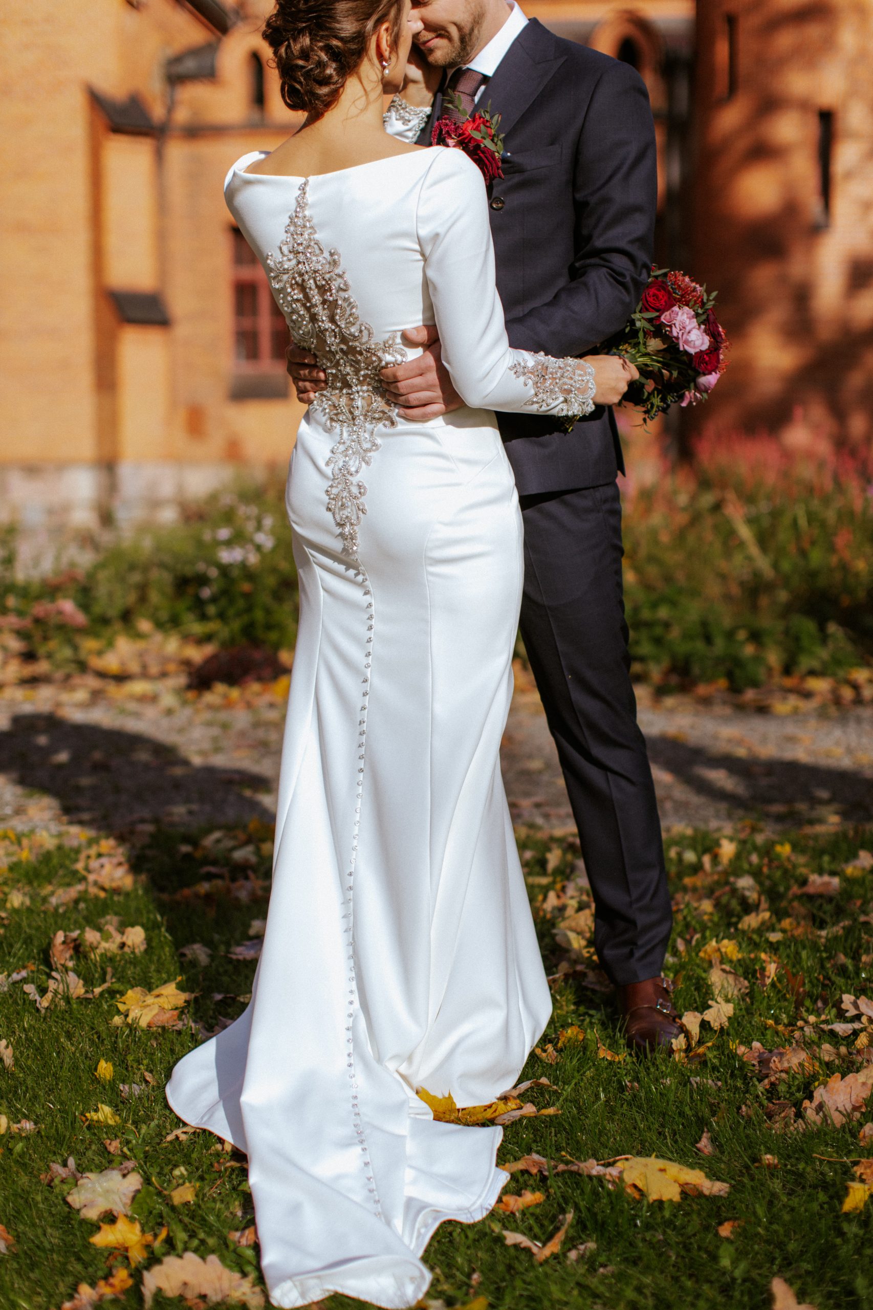 Mariée portant une robe de mariée en crêpe appelée Aston par Sottero et Midgley debout avec le marié en automne