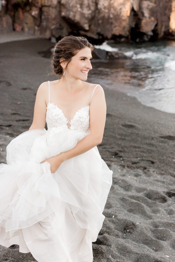 Bride Holding Maggie Sottero Wedding Dress Up as She Walks Along Black Sand Beach