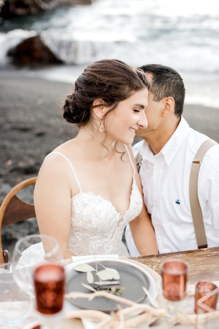 Groom Kissing Real Bride at Wooden Sweetheart Table at Black Sand Beach Elopement Reception