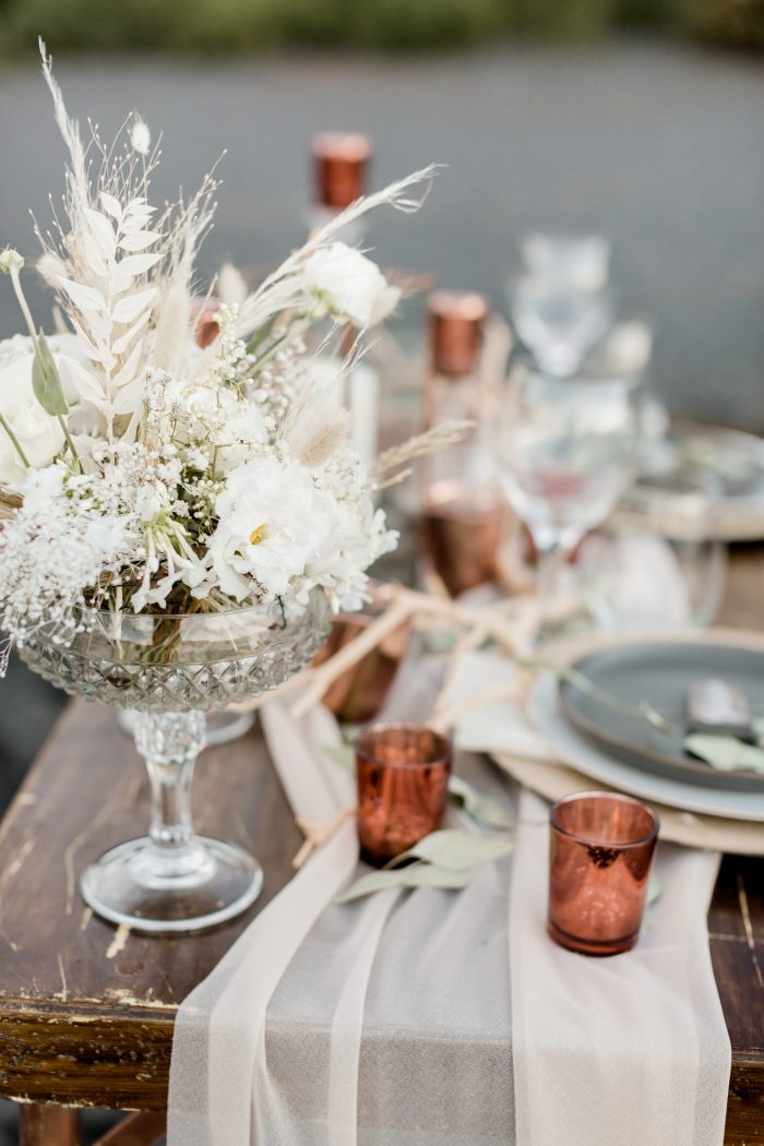 Wooden Table with Golden Candles, Glass Cups, and Floral Centerpieces