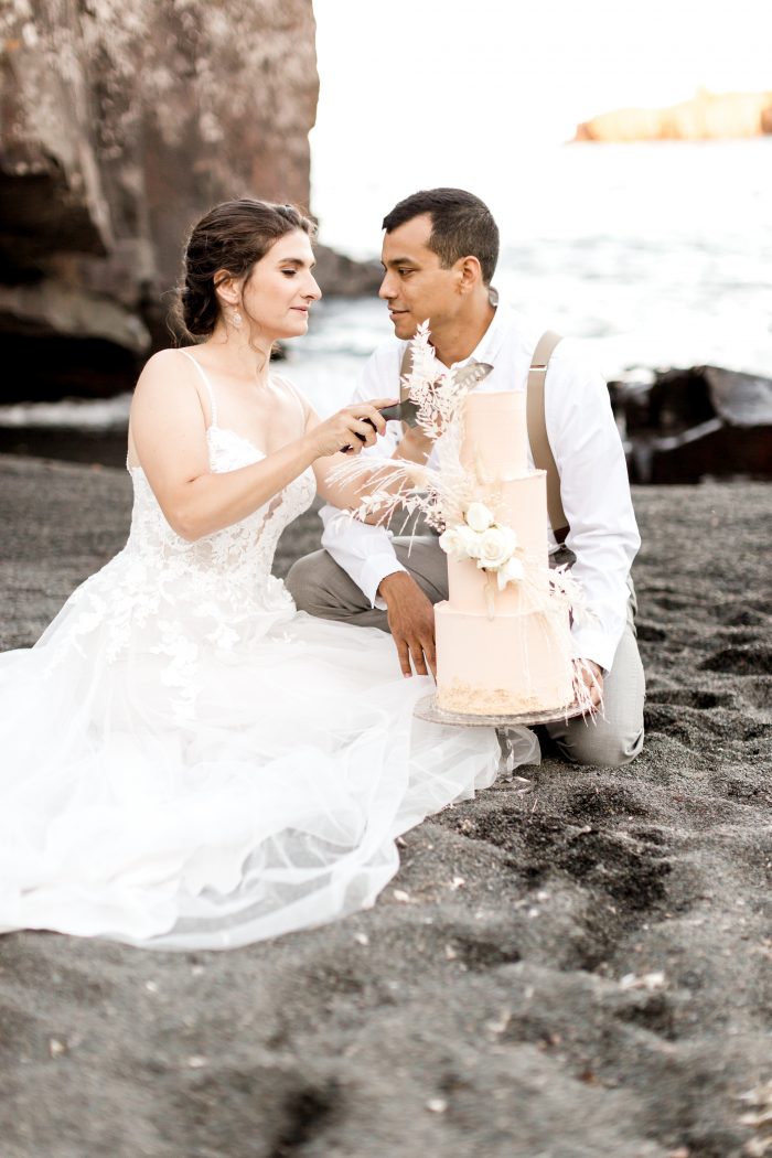 Groom Holding Cake While Bride Cuts Wedding Cake at Intimate Beach Elopement Reception