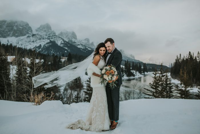 Couple in Wedding Pose in the Mountains While Bride Wearing a Lace Wedding Dress Called Winifred by Sottero and Midgley